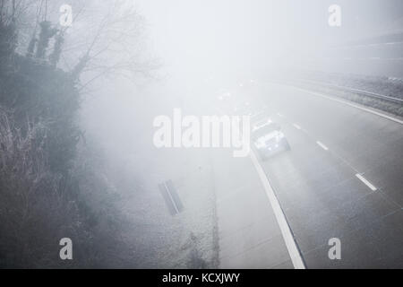 En voiture Les voitures sur la route dans un épais brouillard Banque D'Images