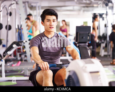Young Asian Woman working out in gym à l'aide d'une machine à ramer. Banque D'Images