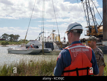 Maître de 1re classe Dave Irvin, gauche, et propriétaire de navire David Rappelet regardez sur les entrepreneurs de construction Laredo et de re-flottante de 38 pieds de rappelet cabin cruiser de Baytown, Texas, le 6 octobre 2017. La Garde côtière travaille avec le Bureau général du Texas et d'autres organismes fédéraux, locaux et des organismes de l'état de recouvrer navires endommagés par l'ouragan Harvey. Photo de la Garde côtière des États-Unis par le Premier maître de Jean Masson. Banque D'Images