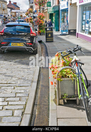 WELLS SOMERSET ANGLETERRE RUE PRINCIPALE MENANT À LA CATHÉDRALE AVEC DE L'EAU PERMANENTE DANS LES RIGOLES OU LES DRAINS DES PUITS OU DES SOURCES Banque D'Images