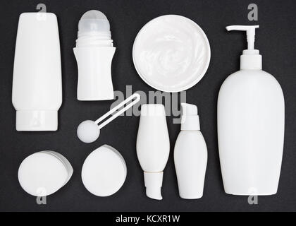 Contenants cosmétiques blanc sur la surface gris foncé. Différents produits cosmétiques pour les soins de la peau des produits cosmétiques de luxe. Banque D'Images