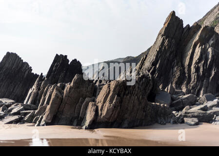 Pierre noire sur une plage avec marée montante, Pembrokeshire , Royaume-Uni Banque D'Images