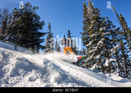 Snowboarder jump dans l'arrière-pays de la neige en poudre. freeride sports d'hiver. Banque D'Images