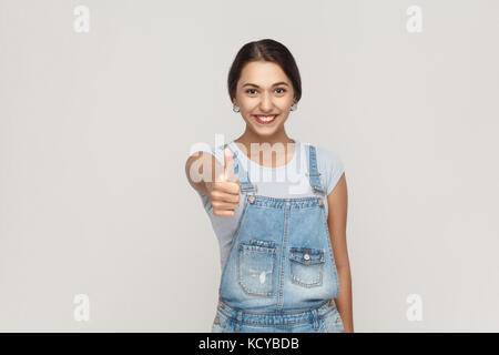 La jeune belle cheerful mixed race woman showing thumb up et sourire à pleines dents et à la recherche à l'appareil photo. studio shot isolé sur fond gris. Banque D'Images