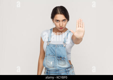 Studio shot isolé sur fond gris. Jeune femme ennuyé avec mauvaise attitude faisant arrêter son geste avec l'extérieur de palm, que personne ne s'exprimant, denia Banque D'Images