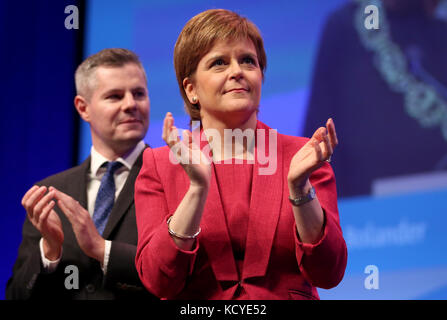 Le premier ministre Nicola Sturgeon et le secrétaire aux Finances Derek Mackay applaudissent après que le vice-premier ministre John Swinney ait prononcé le discours d'ouverture aux délégués à la conférence du Parti national écossais au SEC Centre à Glasgow. Banque D'Images