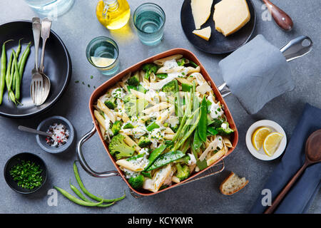 Pâtes aux légumes verts et sauce crémeuse dans une casserole en cuivre. Arrière-plan de pierre grise. Vue d'en haut. Banque D'Images