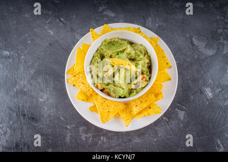 Avec guacamole nachos sur un fond gris. Banque D'Images