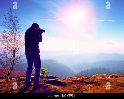 Homme de grande taille est de prendre en photo l'appareil photo miroir sur le cou. snowy piton rocheux de montagne. photographe professionnel prend des photos avec l'appareil photo sur le pic de miroir Banque D'Images