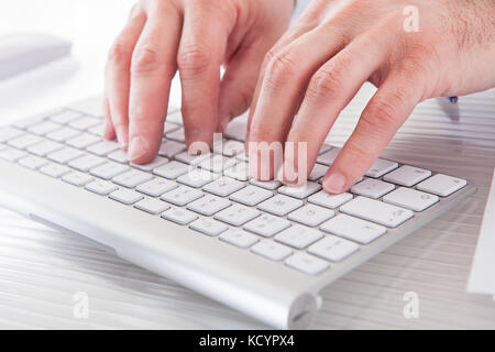 Close-up of male hands typing on computer keyboard Banque D'Images