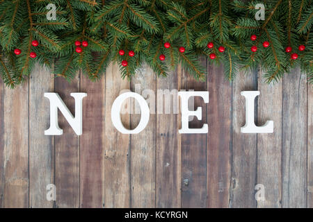 Frontière de noël arbre de Noël naturel de brindilles de sapin, fruits rouges et noel écrit en lettres en bois blanc sur un fond en bois brun avec l'exemplaire Banque D'Images