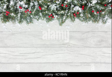 Frontière de noël arbre de Noël naturel de brindilles de sapin et de fruits rouges sur un fond de bois gris recouvert de neige avec copie espace. Banque D'Images