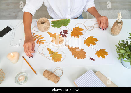 Vue de dessus de femmes faisant des feuilles d'automne composition pour la décoration intérieure Banque D'Images