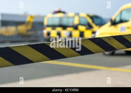 Ruban de signalisation jaune et noir à l'aéroport avec des voitures à l'arrière-plan Banque D'Images