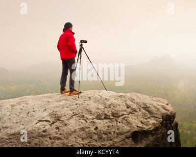 Photographe pensez à photo sur le pic de production dans les montagnes brumeuses. photo ci-dessus à l'aube, caché dans la vallée de la brume lourde. vue paysage de Misty une Banque D'Images