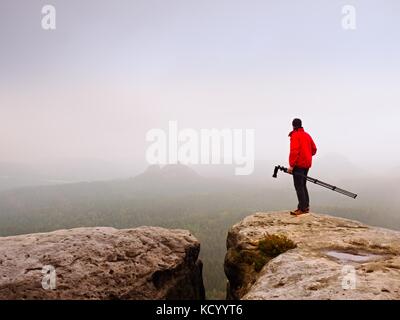 Photographe pensez à photo sur le pic de production dans les montagnes brumeuses. photo ci-dessus à l'aube, caché dans la vallée de la brume lourde. vue paysage de Misty une Banque D'Images