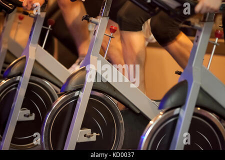 Groupe de quatre personnes de tourner dans la salle de sport, l'exercice de leurs jambes faisant cardio training Banque D'Images