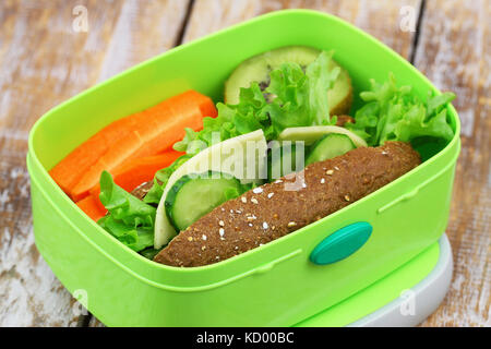 Boîte à lunch saine contenant Brown sandwich au fromage avec de la laitue, carottes croquantes et kiwis Banque D'Images