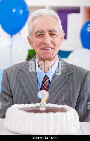 Senior ayant le gâteau d'anniversaire avec une bougie d'interrogation Banque D'Images