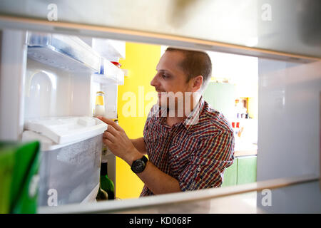 Heureux les hommes trouvés boisson favorite dans un réfrigérateur vide Banque D'Images