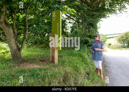 National Trust lady reading informations inscription à peu de Dartmouth, Stoke Fleming, Devon sur la south west coast path Banque D'Images