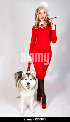 Portrait d'une jeune femme séduisante avec un chien husky sur fond gris Banque D'Images