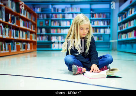 Enfant fille dans public library with book Banque D'Images