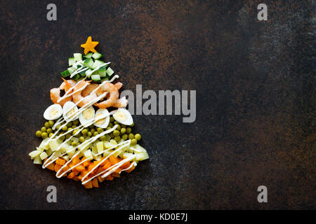 À partir de l'arbre de Noël une salade olivier sur un fond de pierre ou de métal rouillé. Vue de dessus avec une copie. Banque D'Images