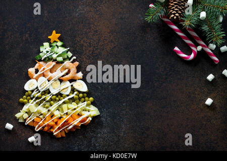 À partir de l'arbre de Noël une salade olivier sur un fond de pierre ou de métal rouillé. Vue de dessus avec une copie. Banque D'Images