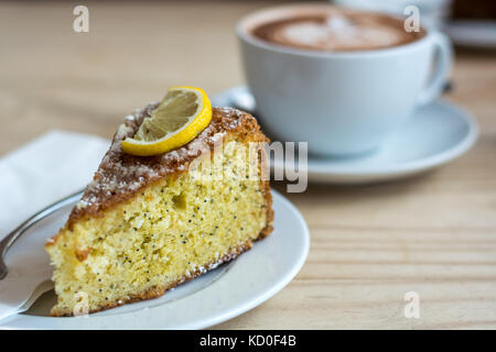 Chocolat chaud avec de la crème en forme de feuille et gâteau au citron sur le côté Banque D'Images