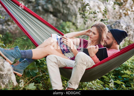 Couple relaxing in hammock reading books, Cracovie, Pologne, europe, malopolskie Banque D'Images