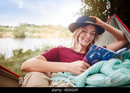 Woman relaxing in hammock reading book, Cracovie, Pologne, europe, malopolskie Banque D'Images