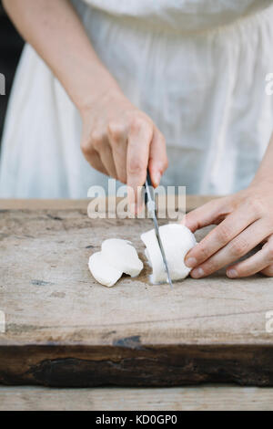 Woman slicing mozzarella sur planche, mid section Banque D'Images