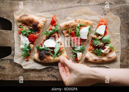 Woman taking pizza slice de planche, overhead view Banque D'Images