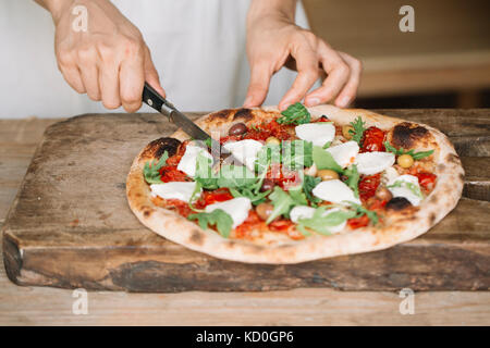 Coupe femme pizza faite maison sur planche, mid section Banque D'Images