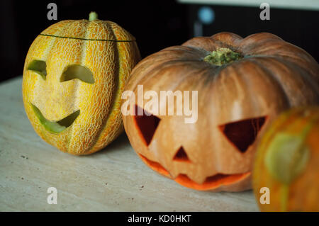 Trois jack-o'-lanternes de citrouille et de melons sur table de cuisine concept fond d'halloween. Banque D'Images