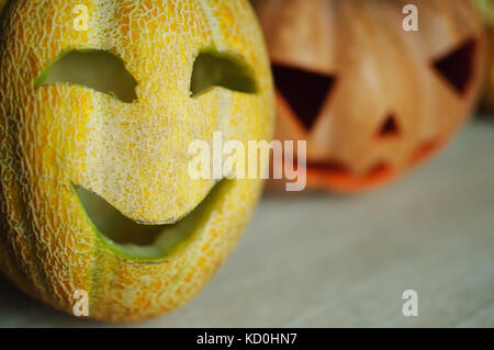 Trois jack-o'-lanternes de citrouille et de melons sur table de cuisine concept fond d'halloween. Banque D'Images