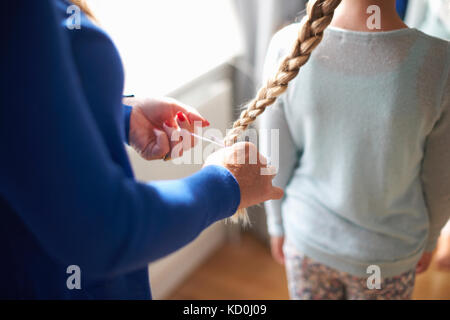 Portrait de mère d'écolière à tresser les cheveux de sa fille Banque D'Images