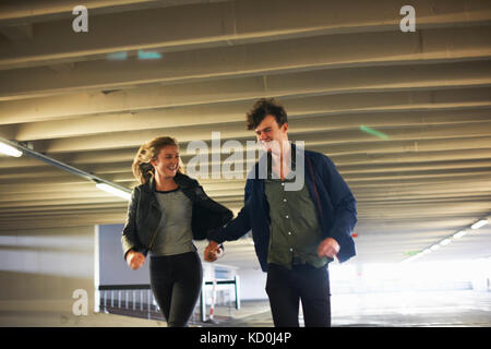 Jeune couple de rire lors de l'exécution par passage souterrain Banque D'Images