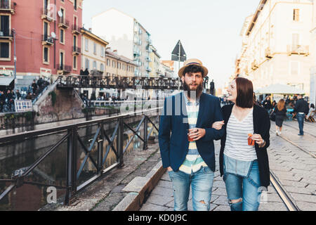 Couple avec cocktails se promener le long du canal de la ville Banque D'Images