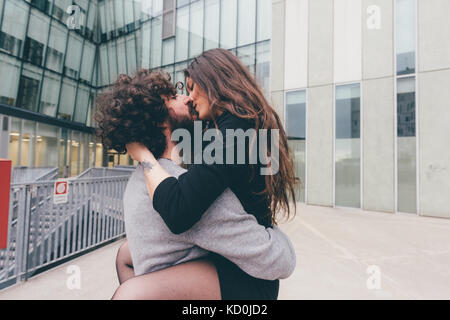 Young couple outdoors, kissing, woman's jambes enroulé autour de l'homme Banque D'Images