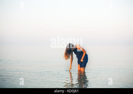 Jeune femme genou profondément en touchant la surface de la mer, Odessa, Ukraine Banque D'Images