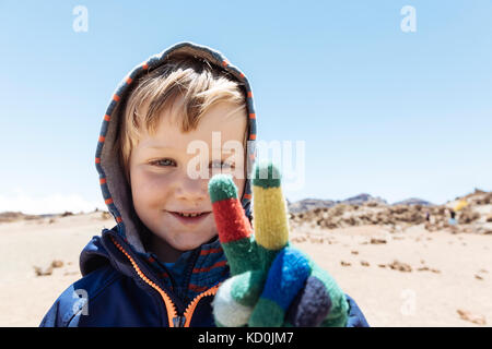 Portrait of cute boy making peace sign avec une main gantée sur le mont Teide, Tenerife, Canary Islands Banque D'Images