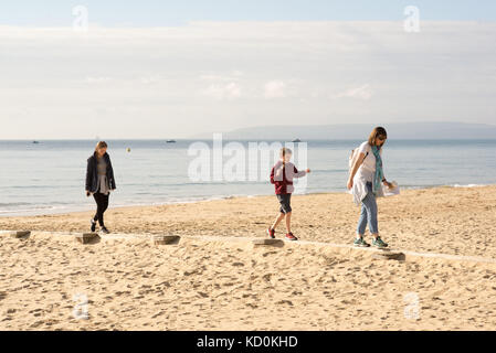 Les gens, la famille, appréciant le temps chaud d'octobre marchant le long et équilibrant un groyne en bois sur la plage au soleil, Bournemouth, Dorset, Royaume-Uni Banque D'Images