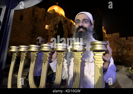 Jérusalem, Israël. 8 octobre 2017. Un juif religieux de la caste sacerdotale Kohanim posant avec la menorah à sept branches (candélabrum) liée au deuxième temple juif créé spécialement pour l'utilisation dans le troisième Temple par l'Institut du Temple de Jérusalem, Prenant part à une reconstitution de la joyeuse cérémonie de la libration de l'eau qui faisait autrefois partie du service du Temple pendant la fête des tabernacles de Soukkot dans la vieille ville de Jérusalem le 08 octobre 2017. L'Institut du Temple ou l'organisation Machon HaMikdash se concentrent sur l'effort de construire le troisième Temple juif. Banque D'Images