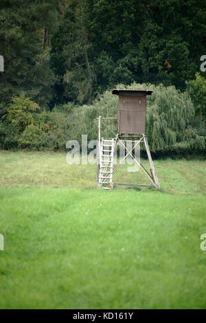 Un siège élevé et camp de chasse se dresse en bordure d'une forêt sur un champ. Banque D'Images