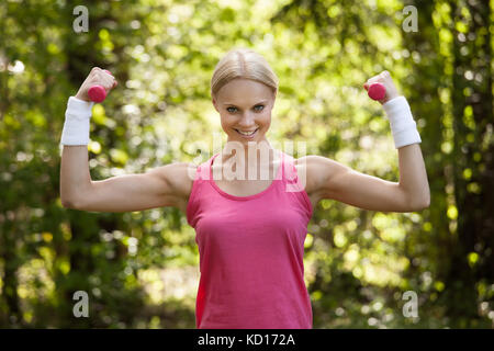 Jeune femme à l'aide d'haltères Pour Workout In Park Banque D'Images