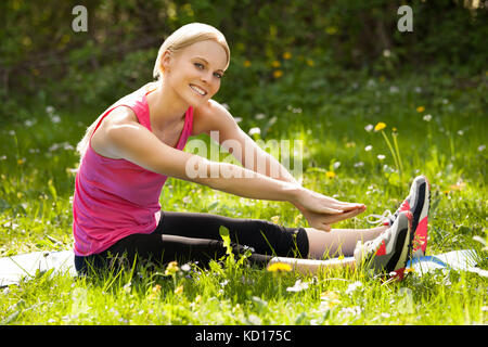Portrait of Young Happy Blonde Woman Stretching Leg Banque D'Images