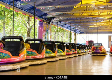 Dodgem colorés voitures alignées sur le côté de la piste en attente d'enfants dans une fête foraine. Banque D'Images