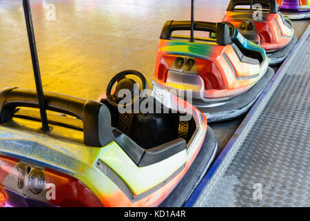 Dodgem colorés voitures alignées sur le côté de la piste en attente d'enfants dans une fête foraine. Banque D'Images